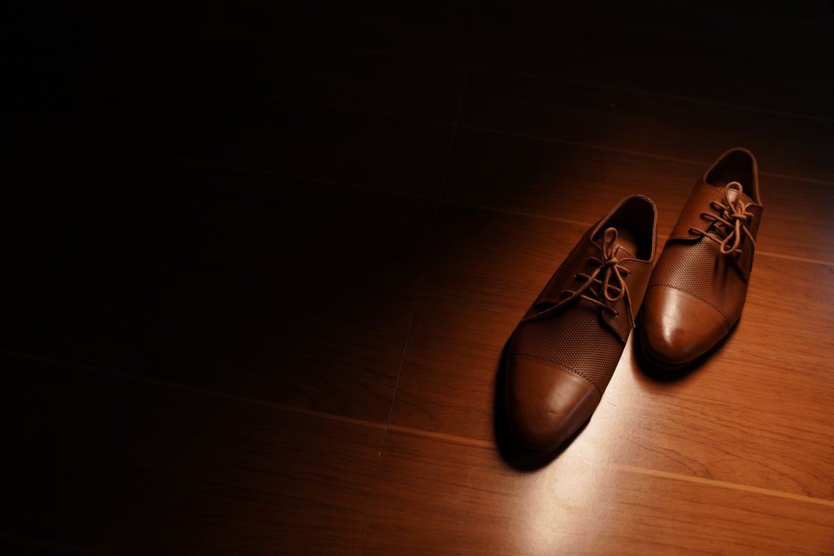 a pair of brown shoes sitting on top of a wooden floor