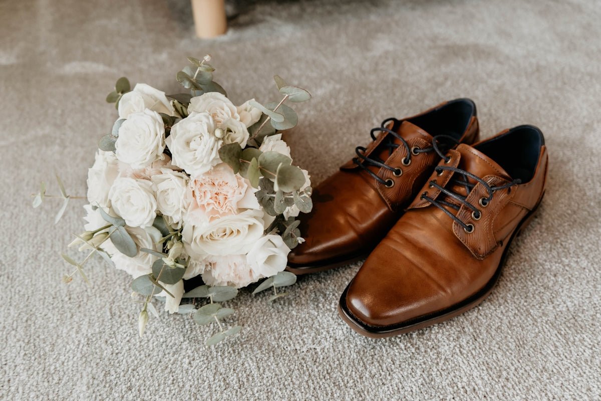 a pair of shoes next to a bouquet of white flowers
