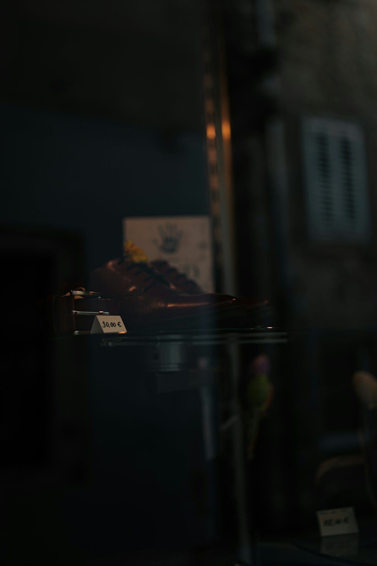 Brown leather shoes displayed in a dark store window.