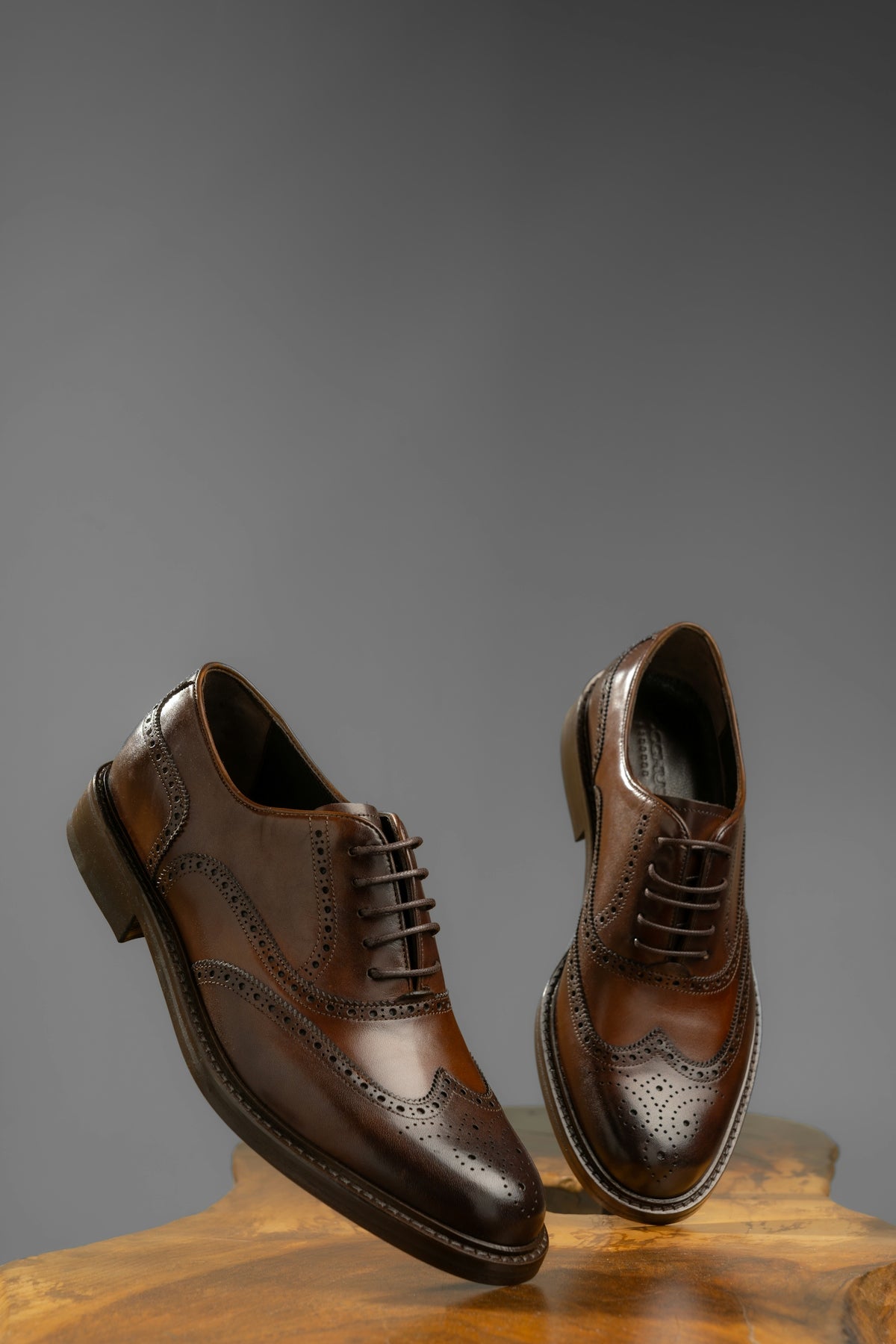 Brown leather wingtip oxford shoes on wooden surface