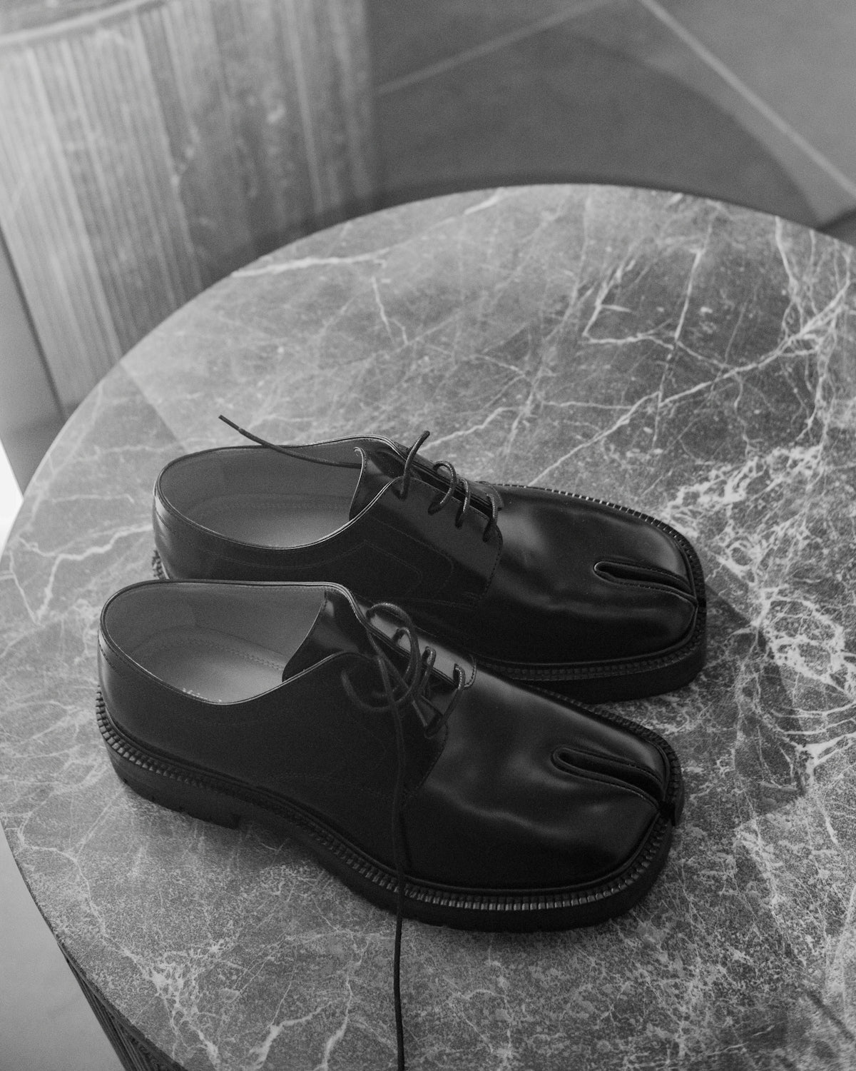 Black leather tabi shoes on a marble table