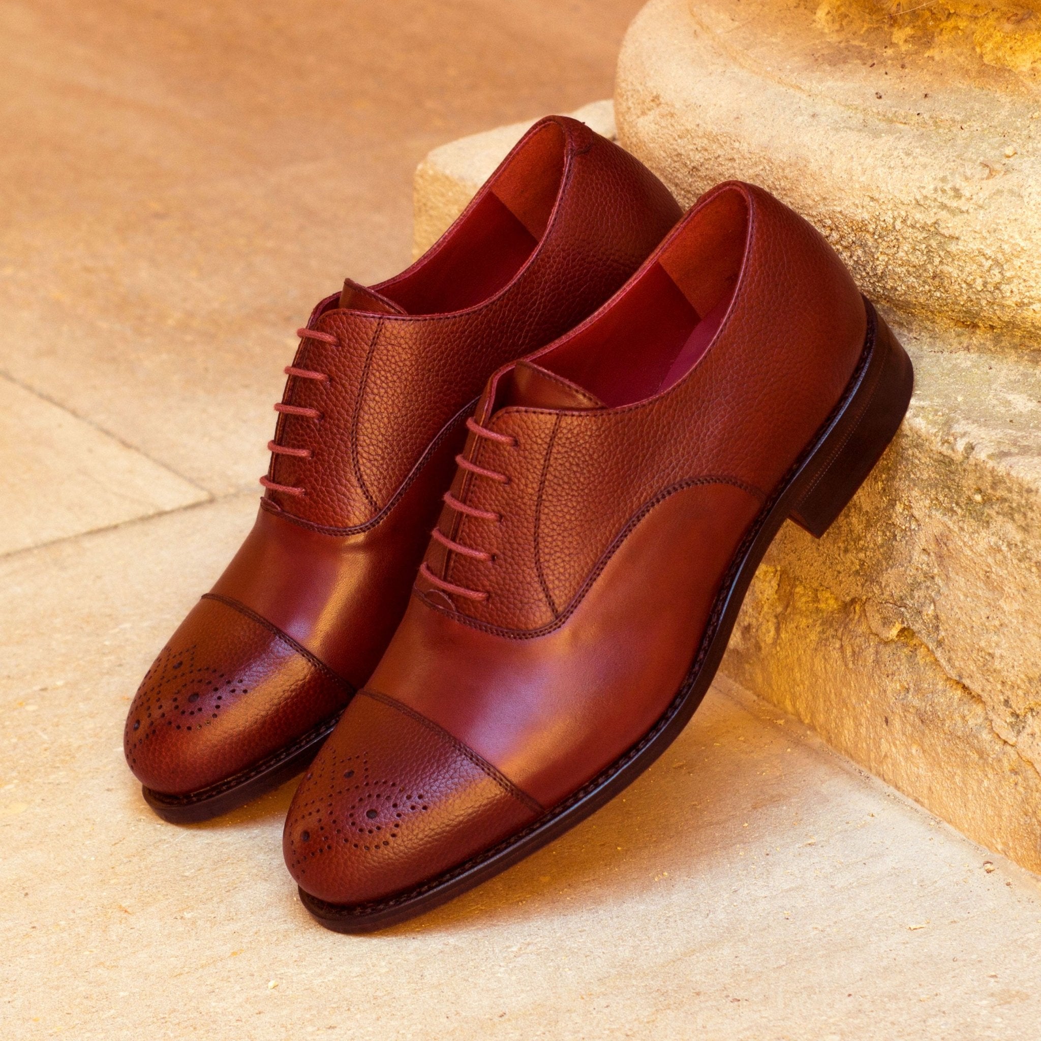 Pair of brown leather dress shoes on a stone surface