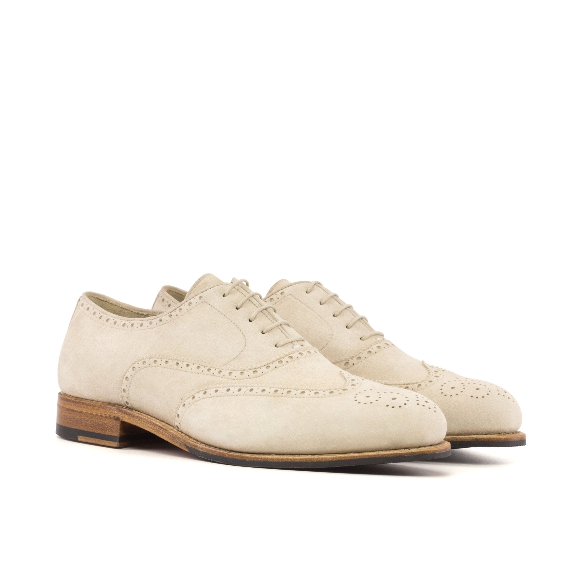 A pair of men's ivory white suede oxford brogue dress shoes with a traditional round toe and a contrasting brown sole visible.