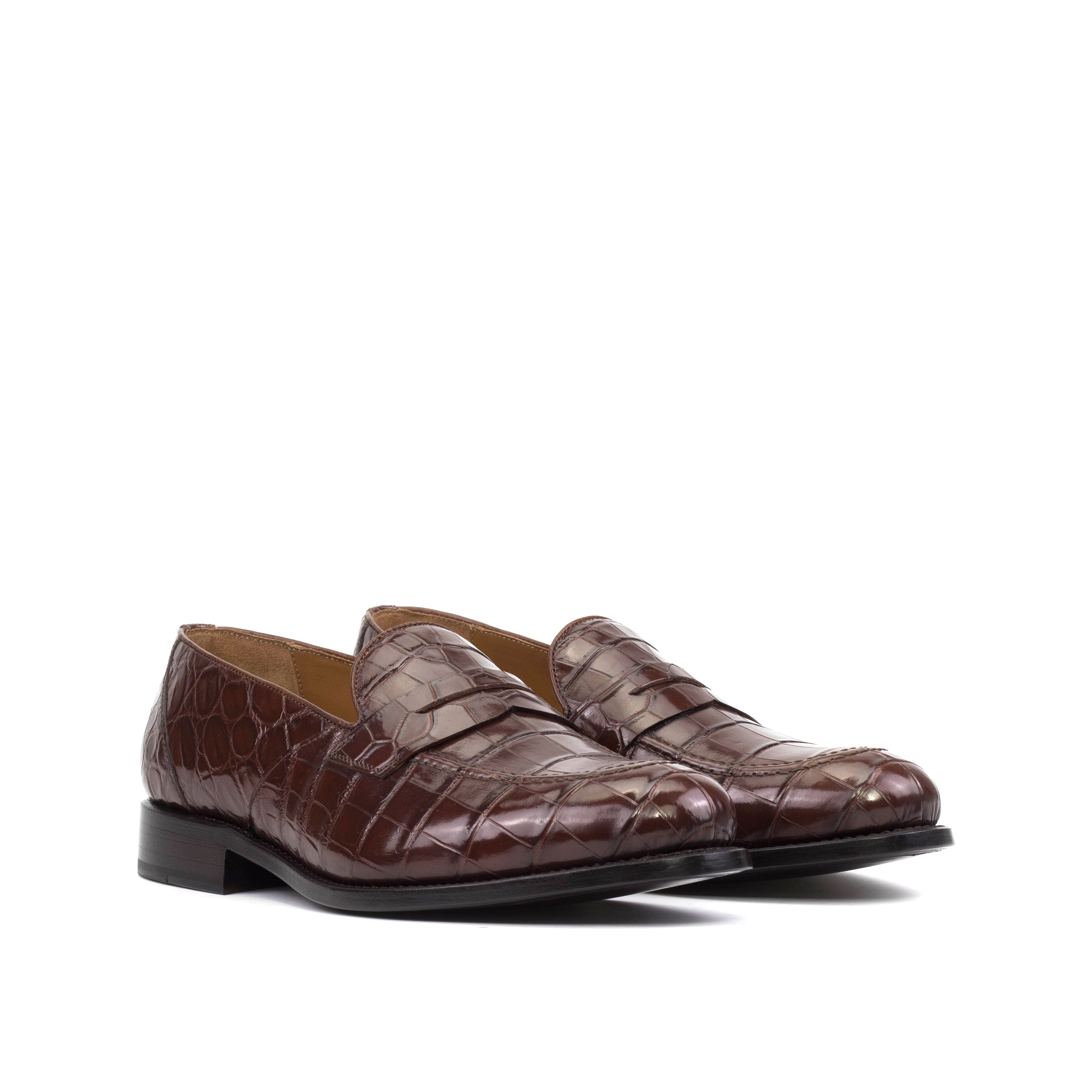 A pair of burgundy loafers with an alligator pattern and a red bottom.