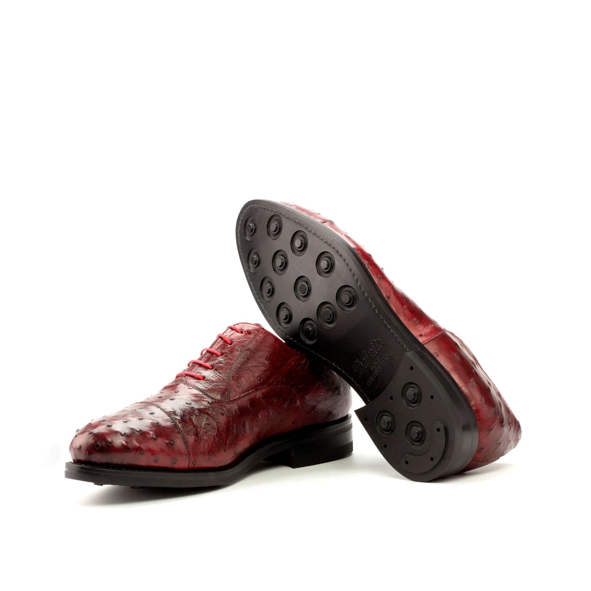 Red leather shoes with black soles on a white background