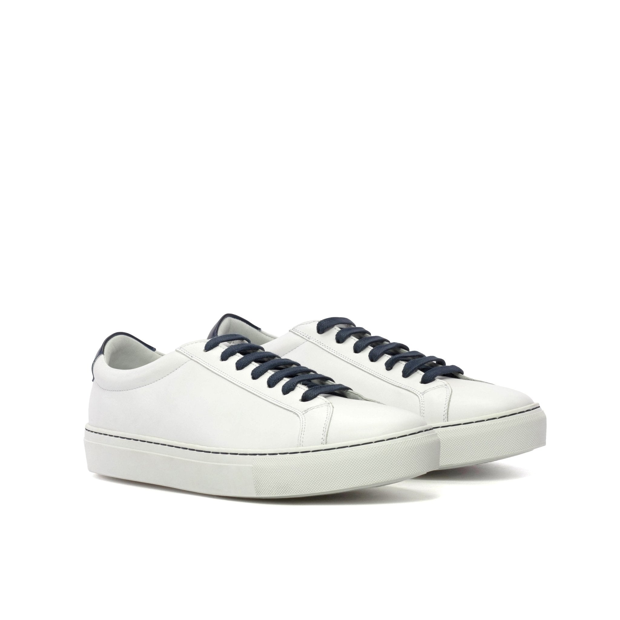 White sneakers with navy laces on a white background
