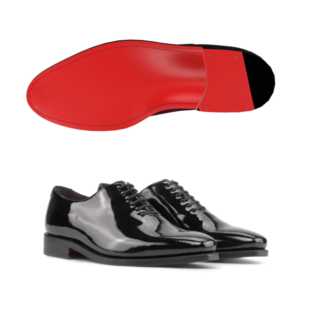 A pair of black shiny patent leather oxford dress shoes with red bottoms.