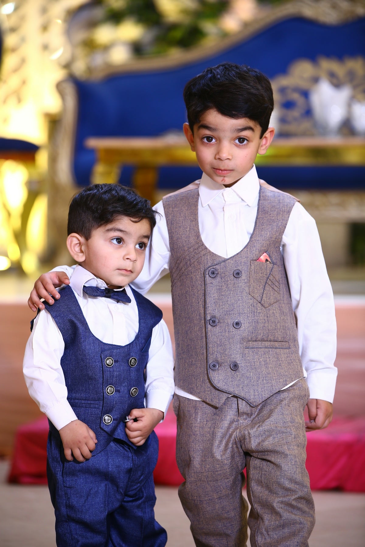 Two young boys dressed in formal wear standing next to each other