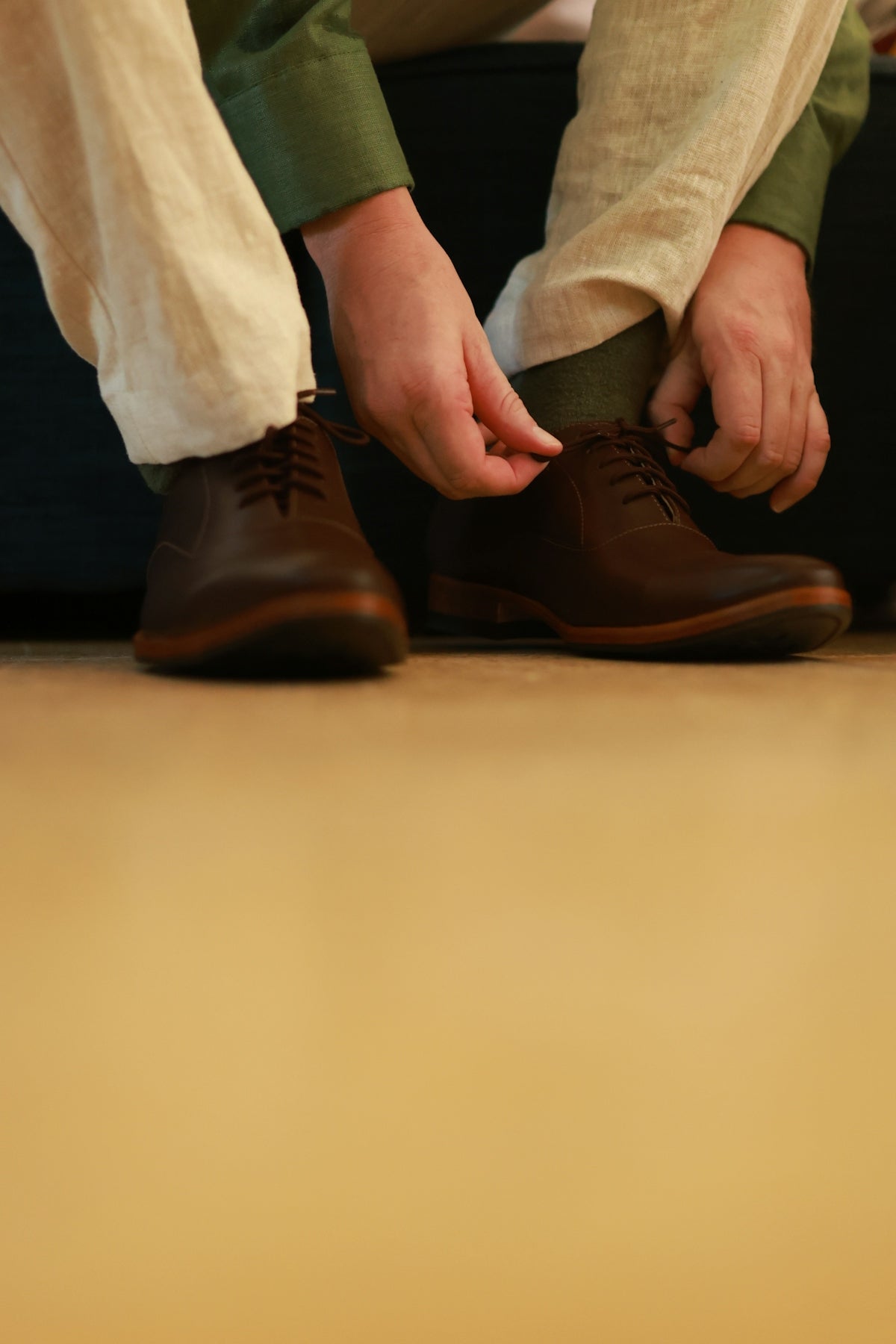 Person tying laces on brown leather oxford shoes.