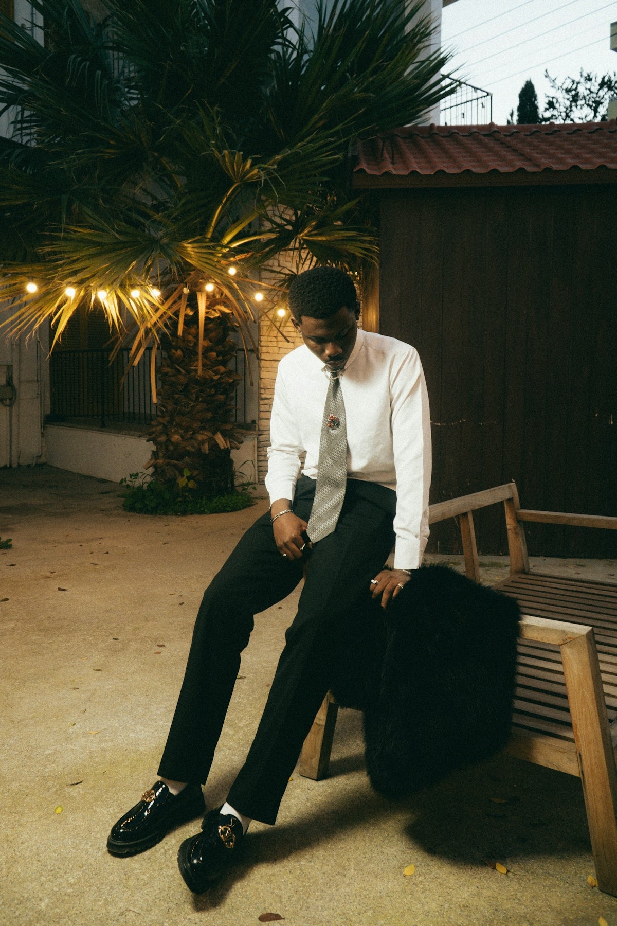Man in formal wear sitting on a bench outdoors