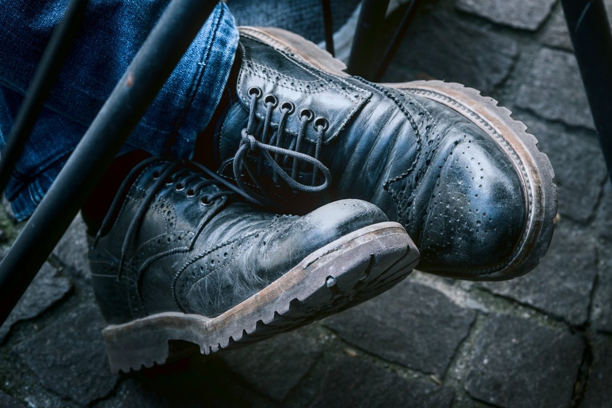 Close up of worn leather shoes and denim jeans.