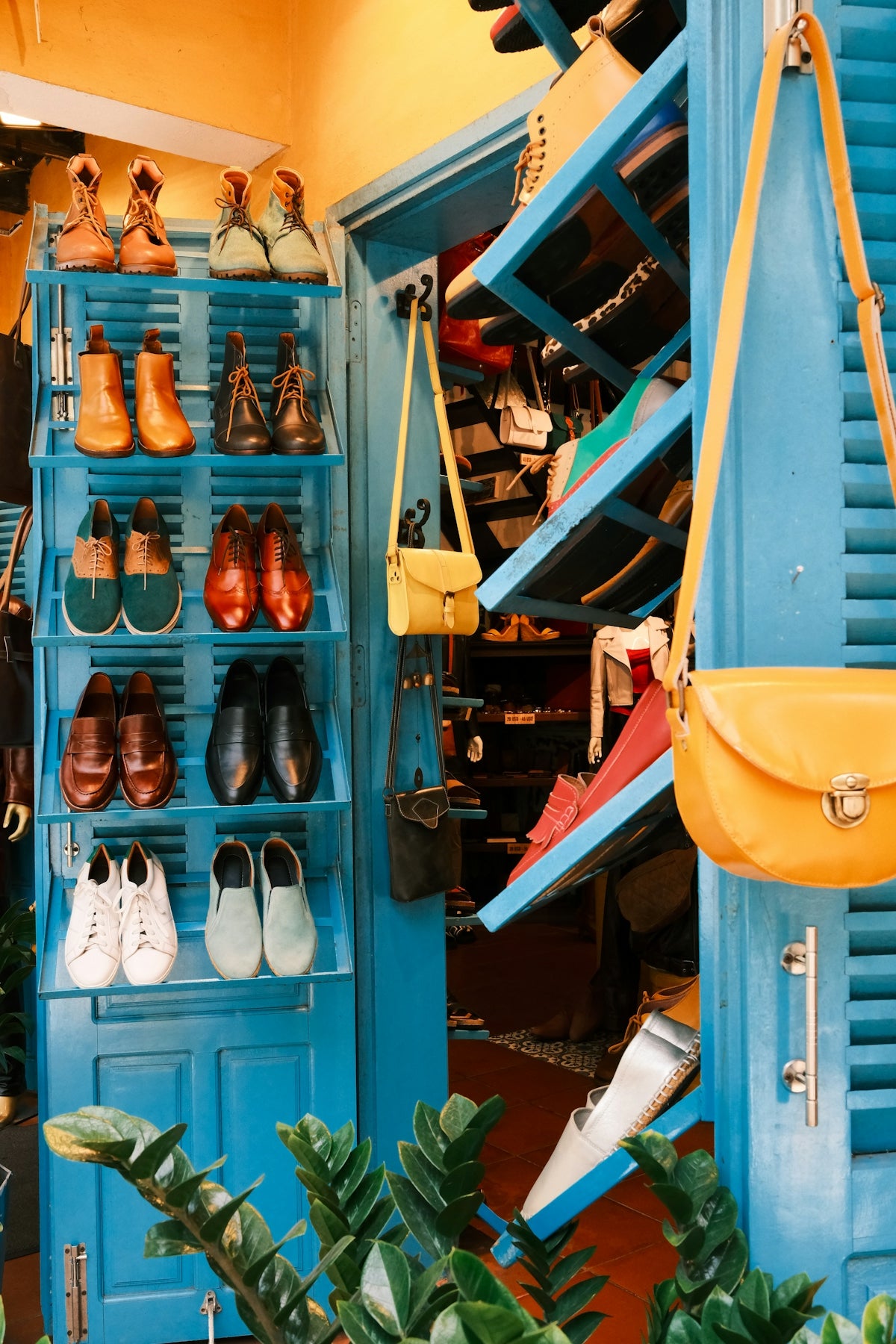 Colorful shoes and yellow handbags displayed on blue shelves.