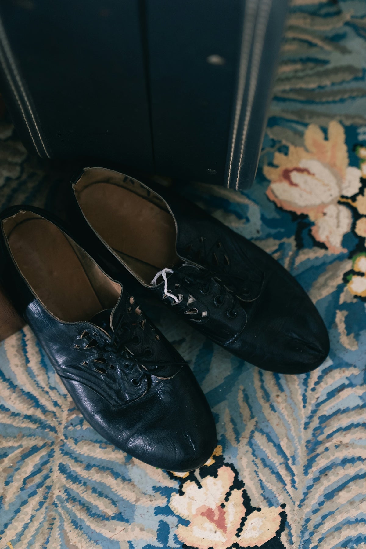 Two black dress shoes sit on a floral patterned rug