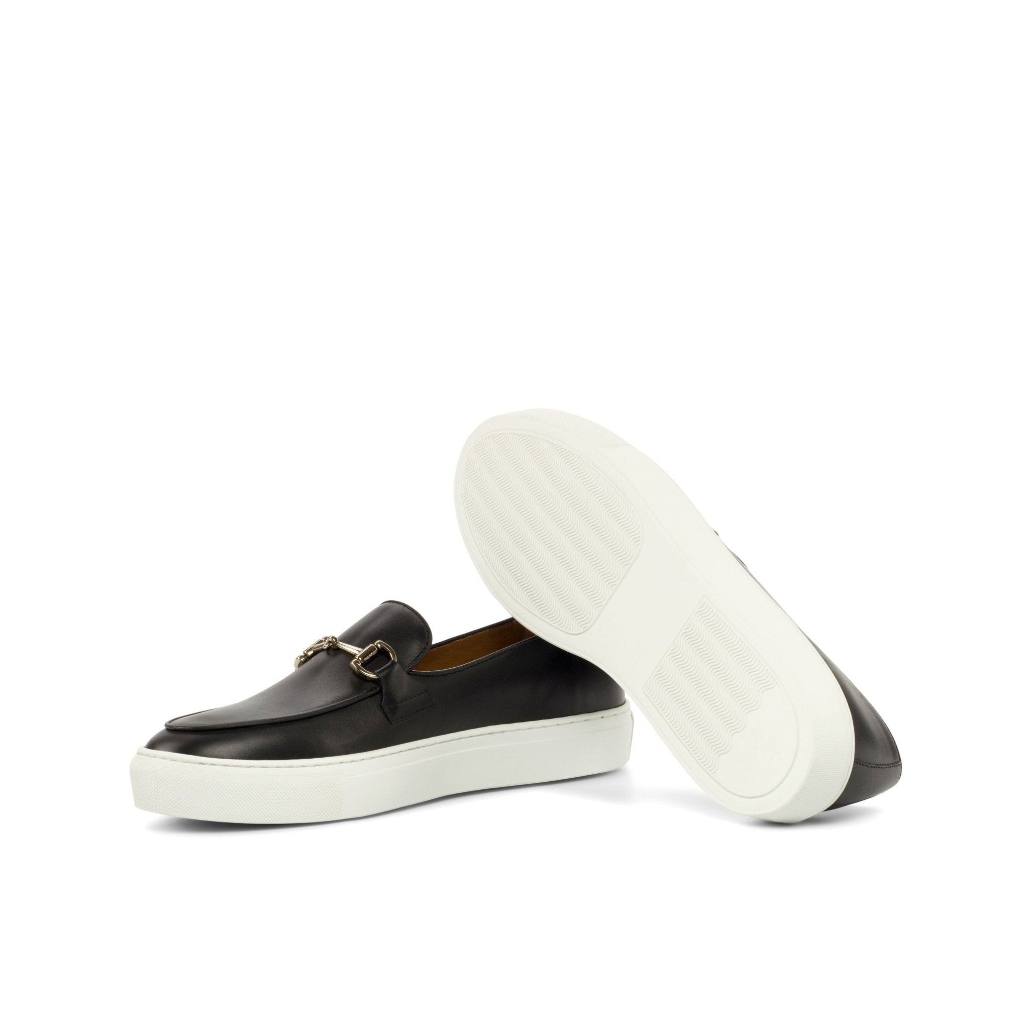 Black loafer shoe with a gold buckle on a white background