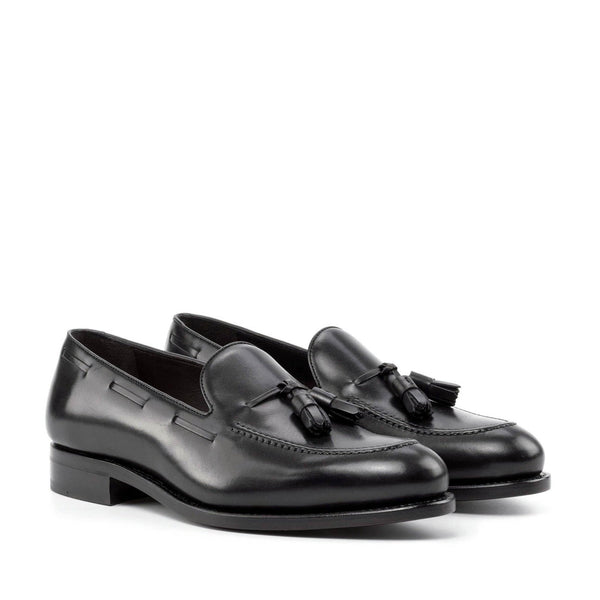 Pair of black loafers with tassels on a white background