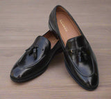 Arconya - A pair of handmade black loafers with a round toe shape and a hand-stitched border on a wooden surface.