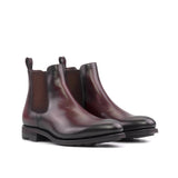 A pair of men's burgundy leather Chelsea boots with a black rubber sole.