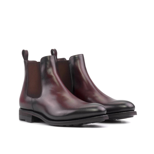 A pair of men's burgundy leather Chelsea boots with a black rubber sole.