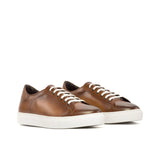 Pair of brown sneakers with white laces on a white background