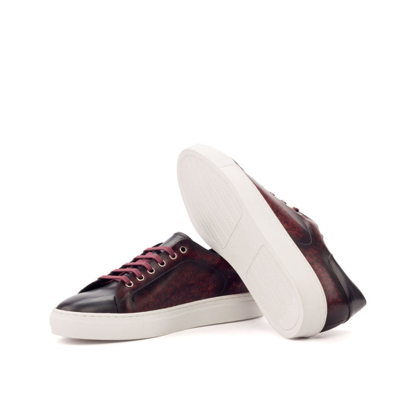 Pair of maroon sneakers with white soles on a white background