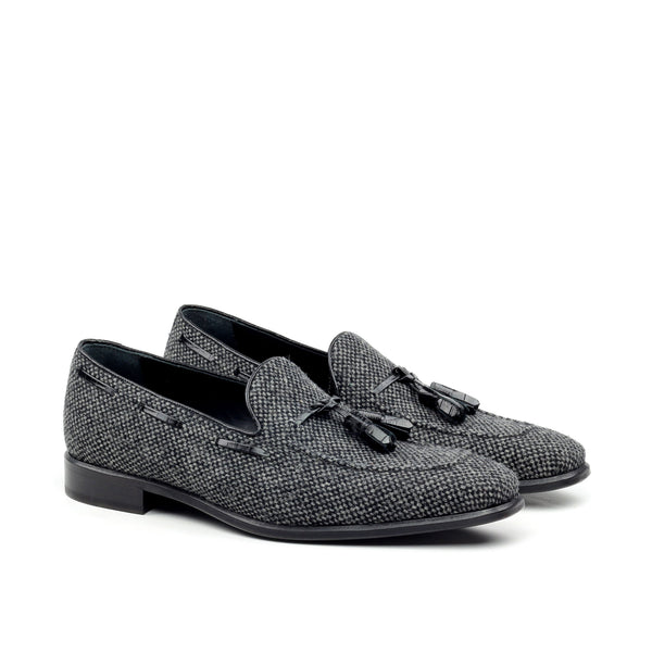 A pair of dark grey flannel tassel loafers with a square toe and low heel.